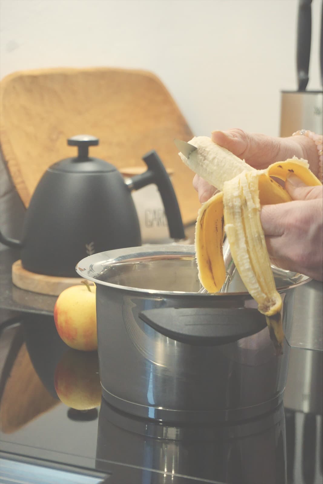 Über einem Kochtopf wird eine Banane geschält
