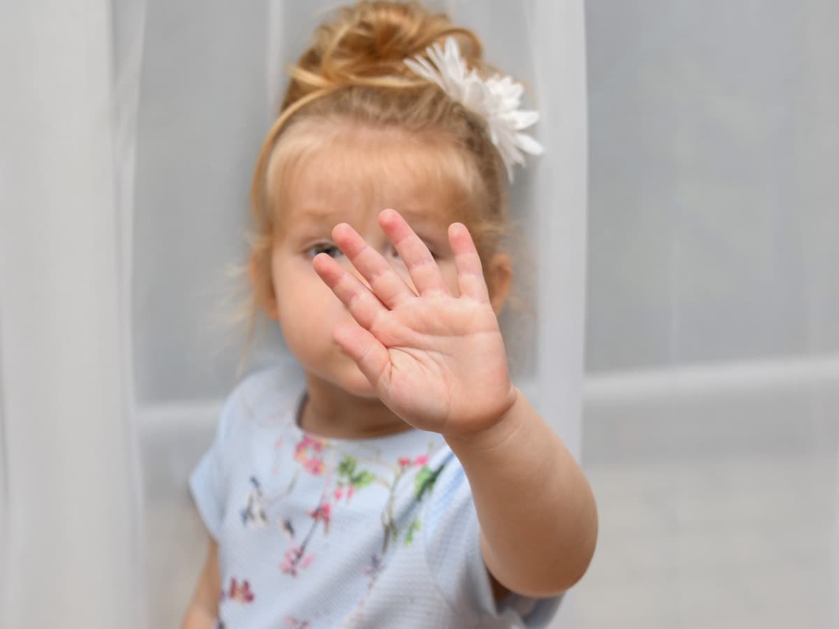 Ein Kleinkind hält die Hand nach vorn, am Fenster